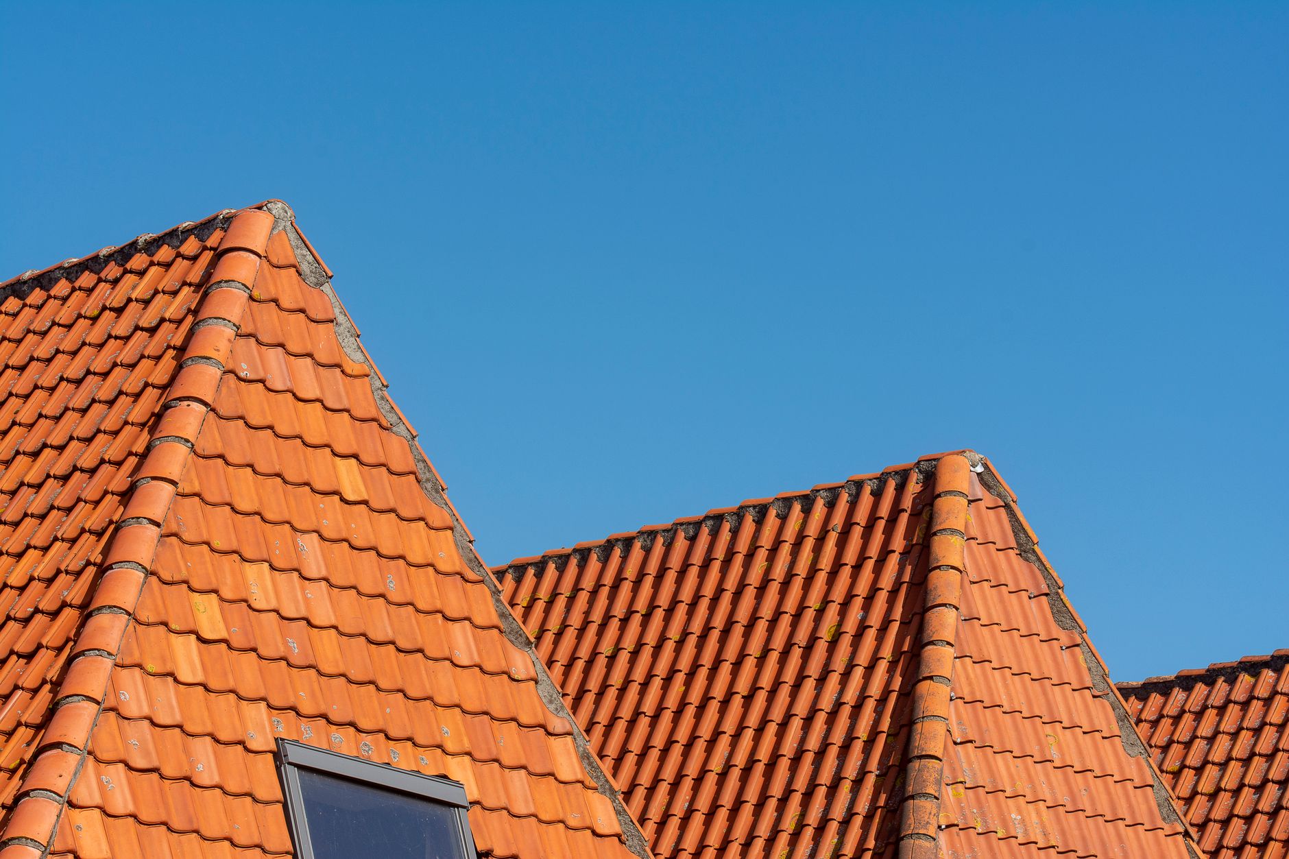 Close-up of red tile roofs under clear blue sky showing architectural design and quality craftsmanship