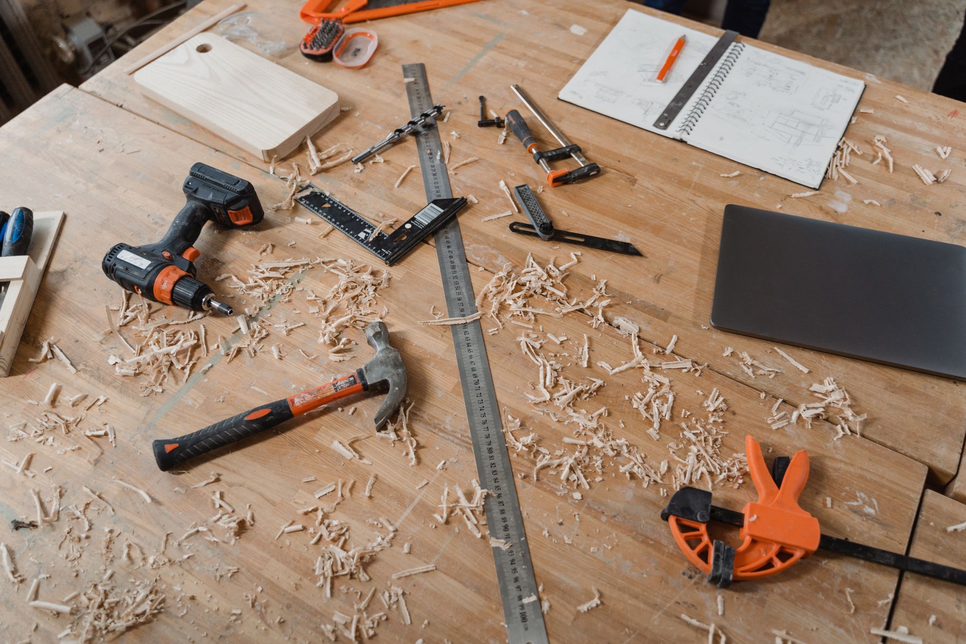 Workbench with various roofing and carpentry tools, including sketches and materials indicating active project